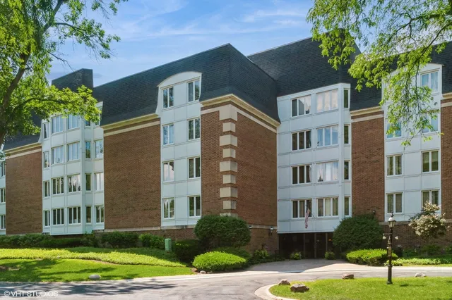 a front view of a residential apartment building with a yard and plants
