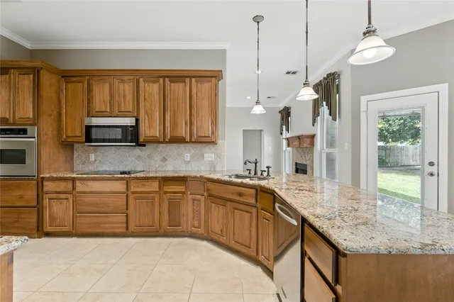a view of a kitchen with kitchen island a sink appliances and a counter top space