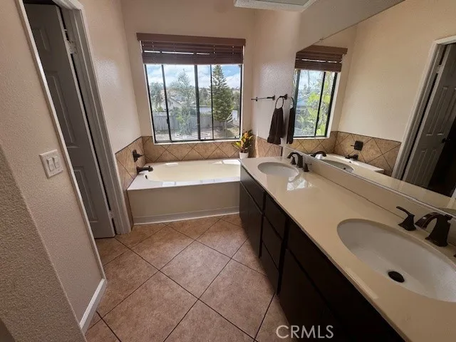 a bathroom with a double vanity sink a mirror and a bathtub