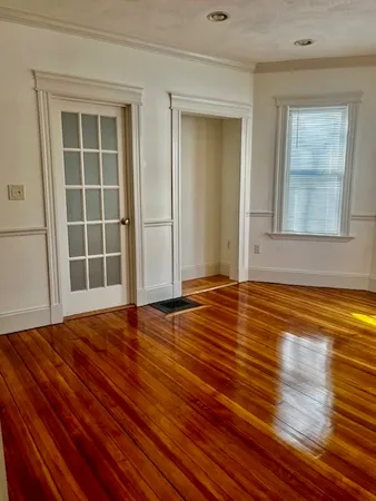 a view of empty room with wooden floor and window