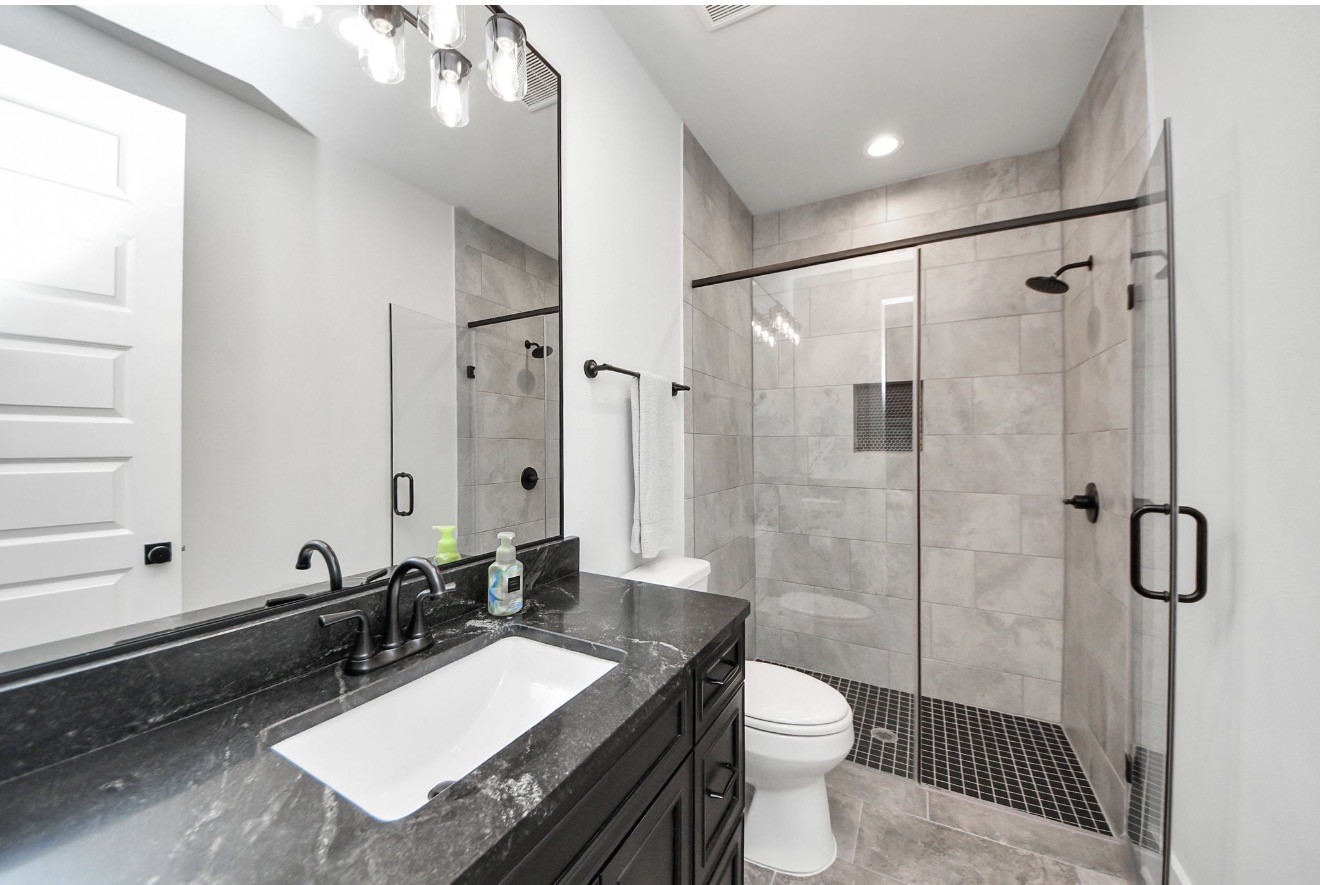 12784 Oak Barrel Road Willis, TX 77378 - Photo 19 of 28 a bathroom with a granite countertop sink toilet a mirror and shower