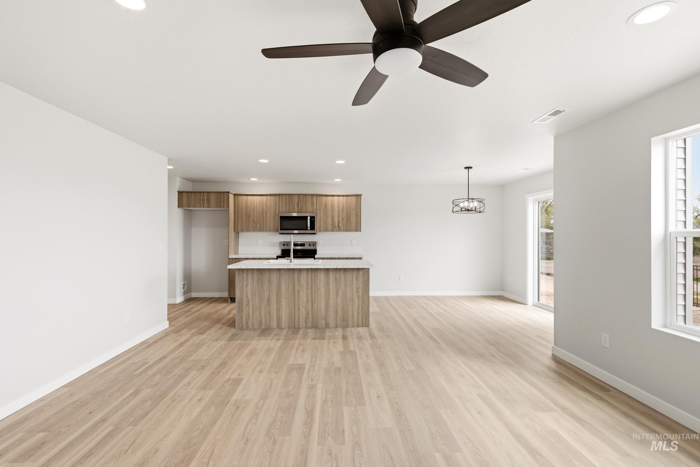 2446 West Fallon Loop Nampa, ID 83651 - Photo 8 of 19 Kitchen with a ceiling fan, wood finish cabinets, light wood finished floors, a center island with sink, and stainless steel appliances