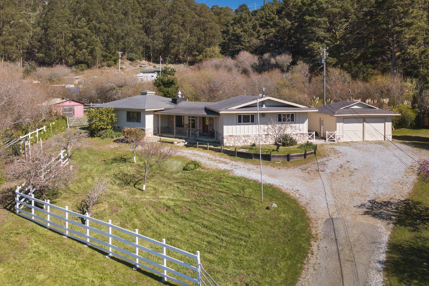 991 Zamora Drive Pacifica, CA 94044 - Photo 3 of 26 a view of a white house with a large pool and lawn chairs under an umbrella