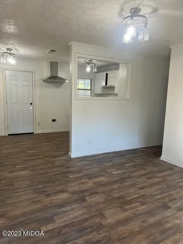 a view of kitchen and empty room with wooden floor