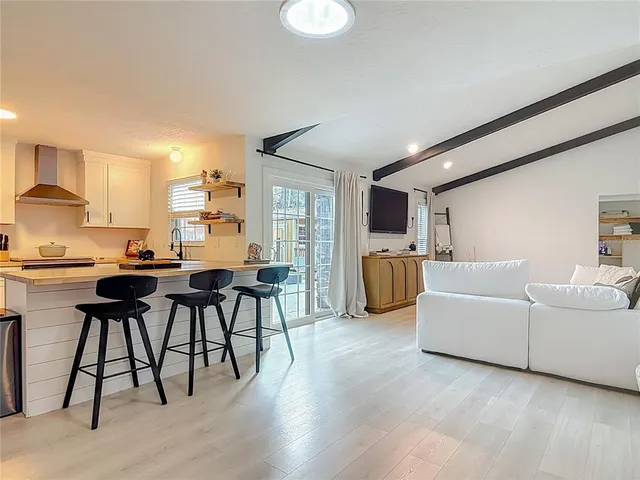 a living room with furniture kitchen view and a wooden floor