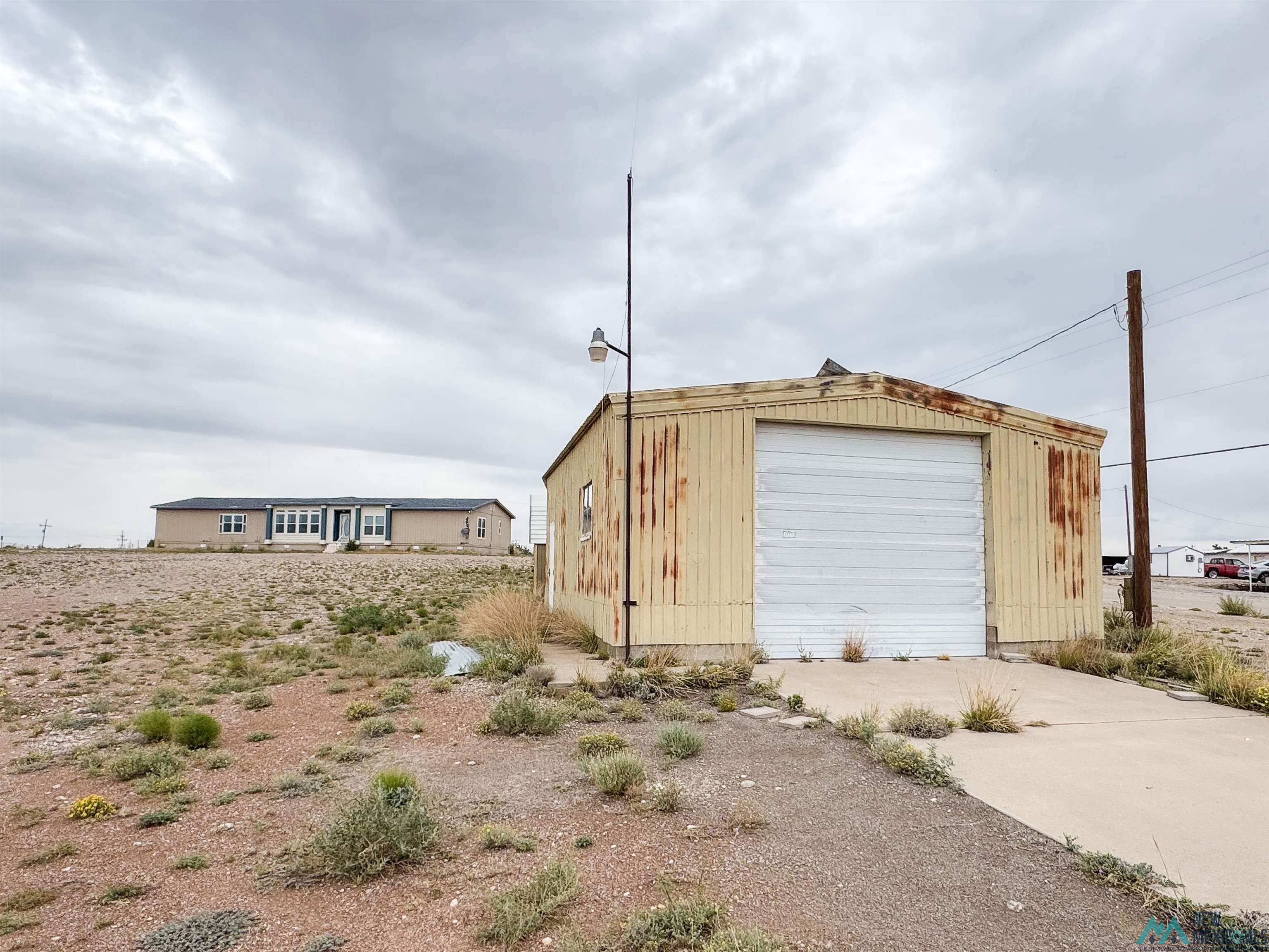 309 Crossbow Road Artesia, NM 88210 - Photo 29 of 31 Detached metal utility building featuring a white roll-up door and exterior lighting