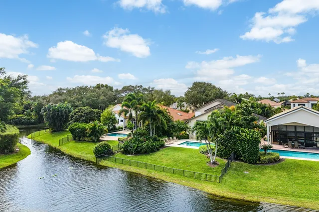 a view of a house with a big yard and potted plants and large trees