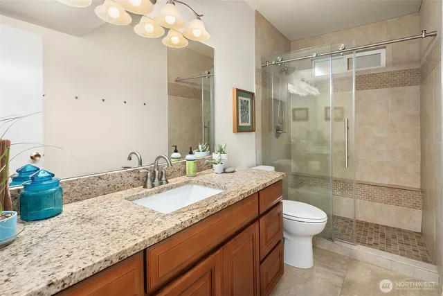 a bathroom with a granite countertop sink a toilet and shower