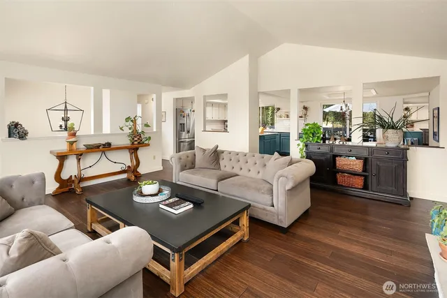 a living room with furniture couches and a dining table with wooden floor