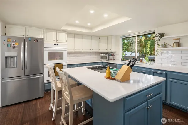 a kitchen with stainless steel appliances granite countertop a sink a stove a refrigerator a microwave oven with cabinets and wooden floor