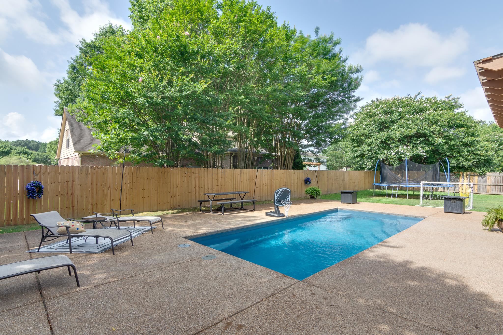 779 Early Earner Cove Collierville, TN 38017 - Photo 26 of 29 Expansive backyard featuring a rectangular in-ground pool with a surrounding concrete patio, a wooden privacy fence, and mature trees providing natural screening
