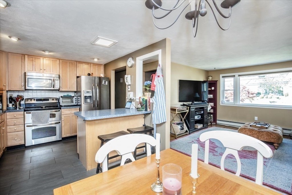 142 Spring Street Stoneham, MA 02180 - Photo 11 of 27 a large kitchen with cabinets a sink a window and stainless steel appliances
