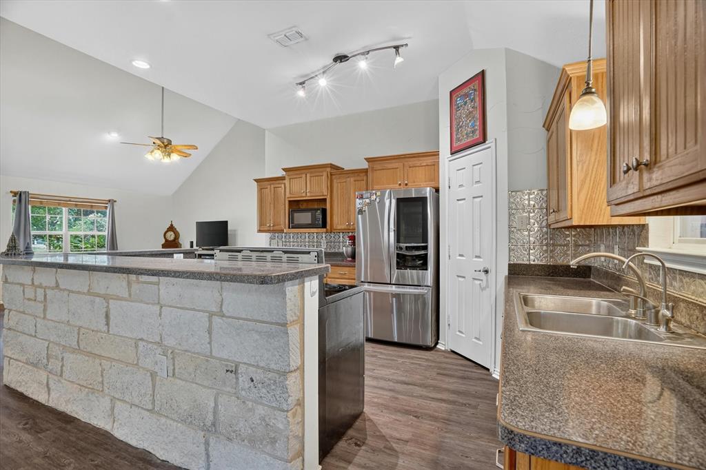 1654 Ranger Highway Weatherford, TX 76088 - Photo 15 of 31 Kitchen featuring stone-clad island with countertop, wood-finish flooring, stainless steel appliances, and wood cabinetry