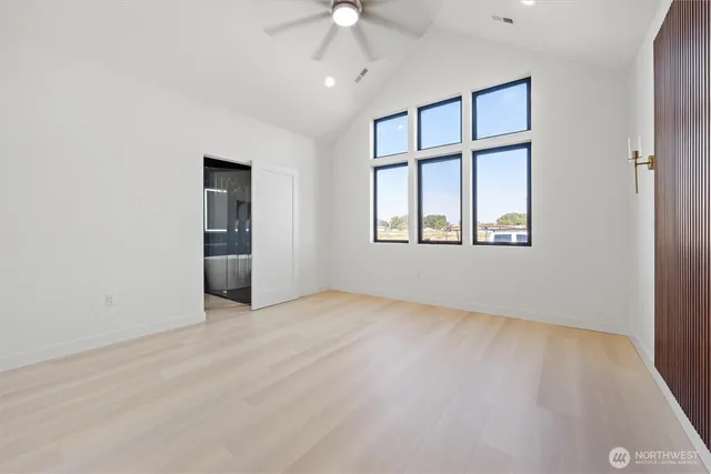 an empty room with chandelier fan and windows