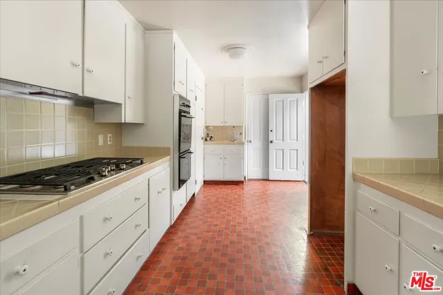a kitchen with white cabinets and appliances