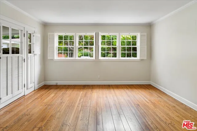 a view of an empty room with wooden floor and a window