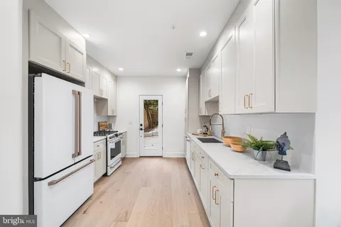 a kitchen with white cabinets and refrigerator