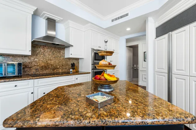 a kitchen with granite countertop a refrigerator and a stove top oven