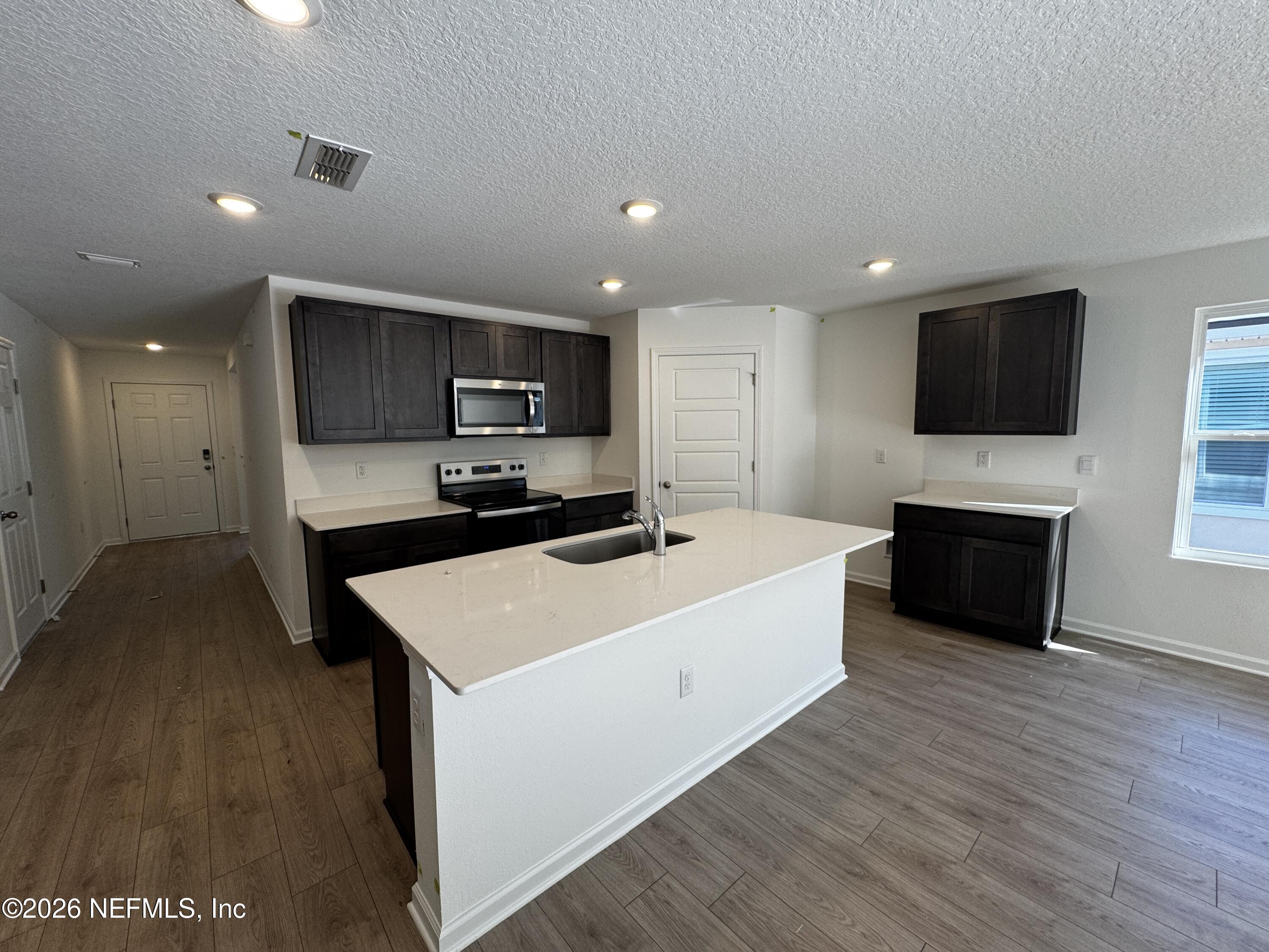 12390 Great Eagle Road Jacksonville, FL 32219 - Photo 10 of 69 a large white kitchen with a stove a sink and a microwave