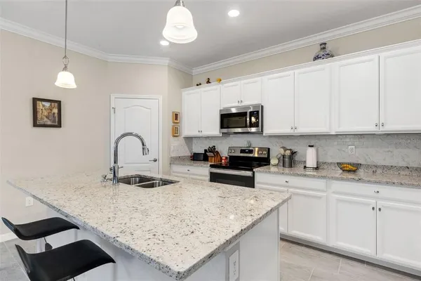 a kitchen with granite countertop a sink a stove top oven a dining table and chairs