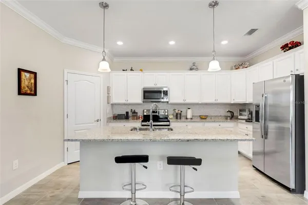 a kitchen with stainless steel appliances granite countertop a refrigerator a sink dishwasher a stove and white cabinets with wooden floor