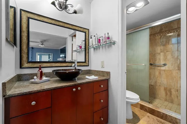 a bathroom with a granite countertop sink a mirror and a toilet