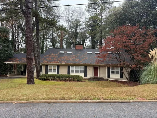 a front view of a house with a yard and large tree