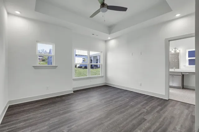 a view of an empty room with wooden floor and a ceiling fan