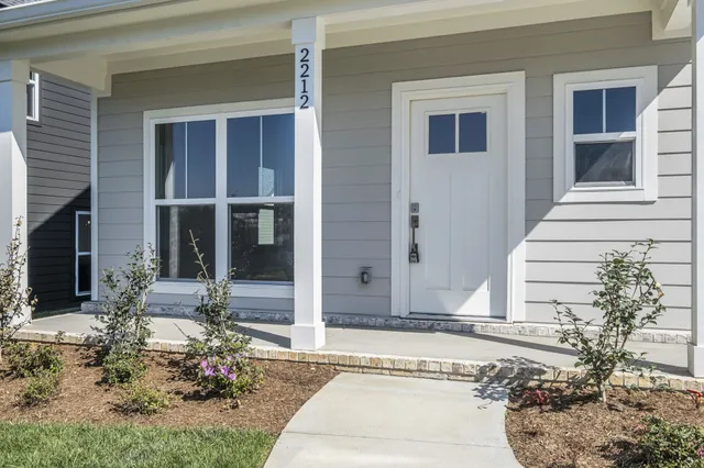 a view of a living room a kitchen with wooden floor and a ceiling fan