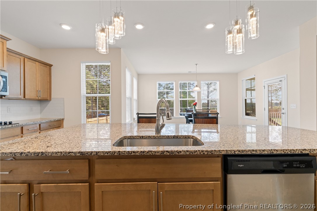18 Two Belles Court Angier, NC 27501 - Photo 9 of 39 a kitchen with granite countertop a stove a sink dishwasher a dining table and chairs with wooden floor