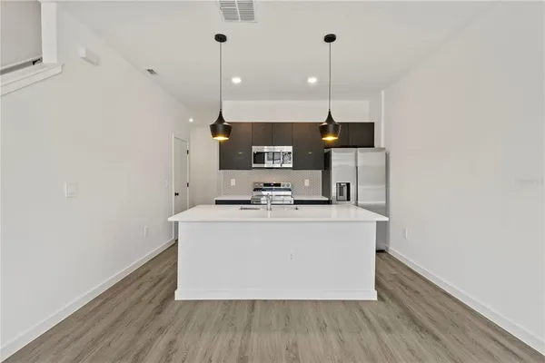 a view of kitchen with stainless steel appliances granite countertop a stove and a wooden floors
