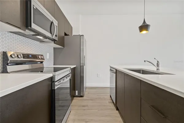 a kitchen that has a sink and a stove with wooden floor