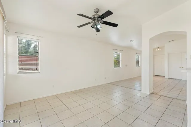 an empty room with chandelier fan and windows