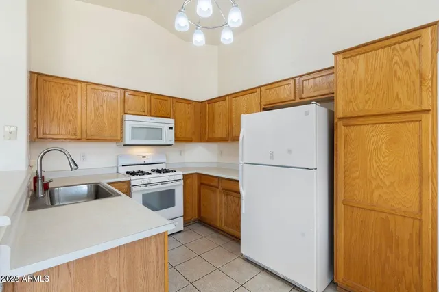 a kitchen with a refrigerator a stove a sink cabinets and a dining table