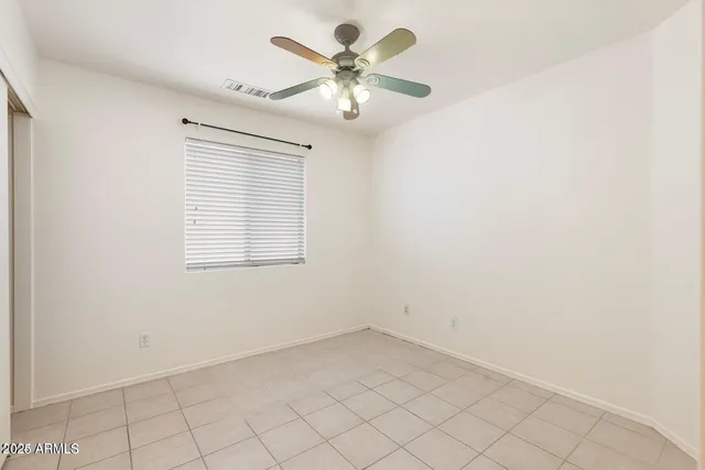 an empty room with chandelier fan and window