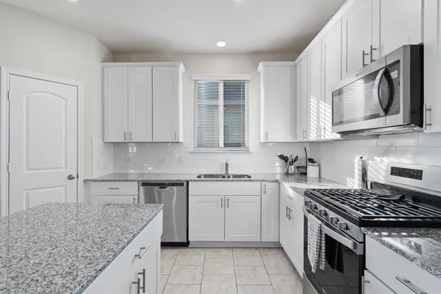 a kitchen with stainless steel appliances granite countertop a stove a sink and a microwave