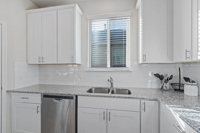 a kitchen with stainless steel appliances granite countertop white cabinets and a sink