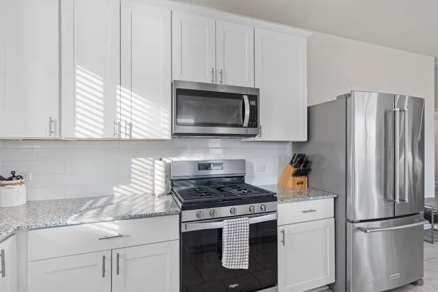 a kitchen with granite countertop white cabinets and stainless steel appliances