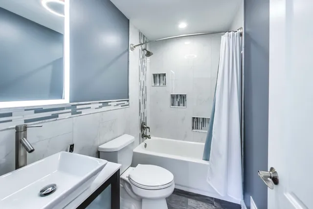 a bathroom with a bathtub shower sink vanity and toilet
