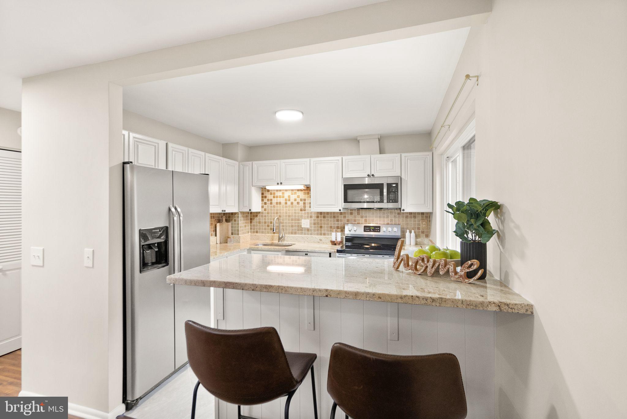 11801 Coopers Court Reston, VA 20191 - Photo 18 of 66 a kitchen with stainless steel appliances a dining table chairs microwave and sink