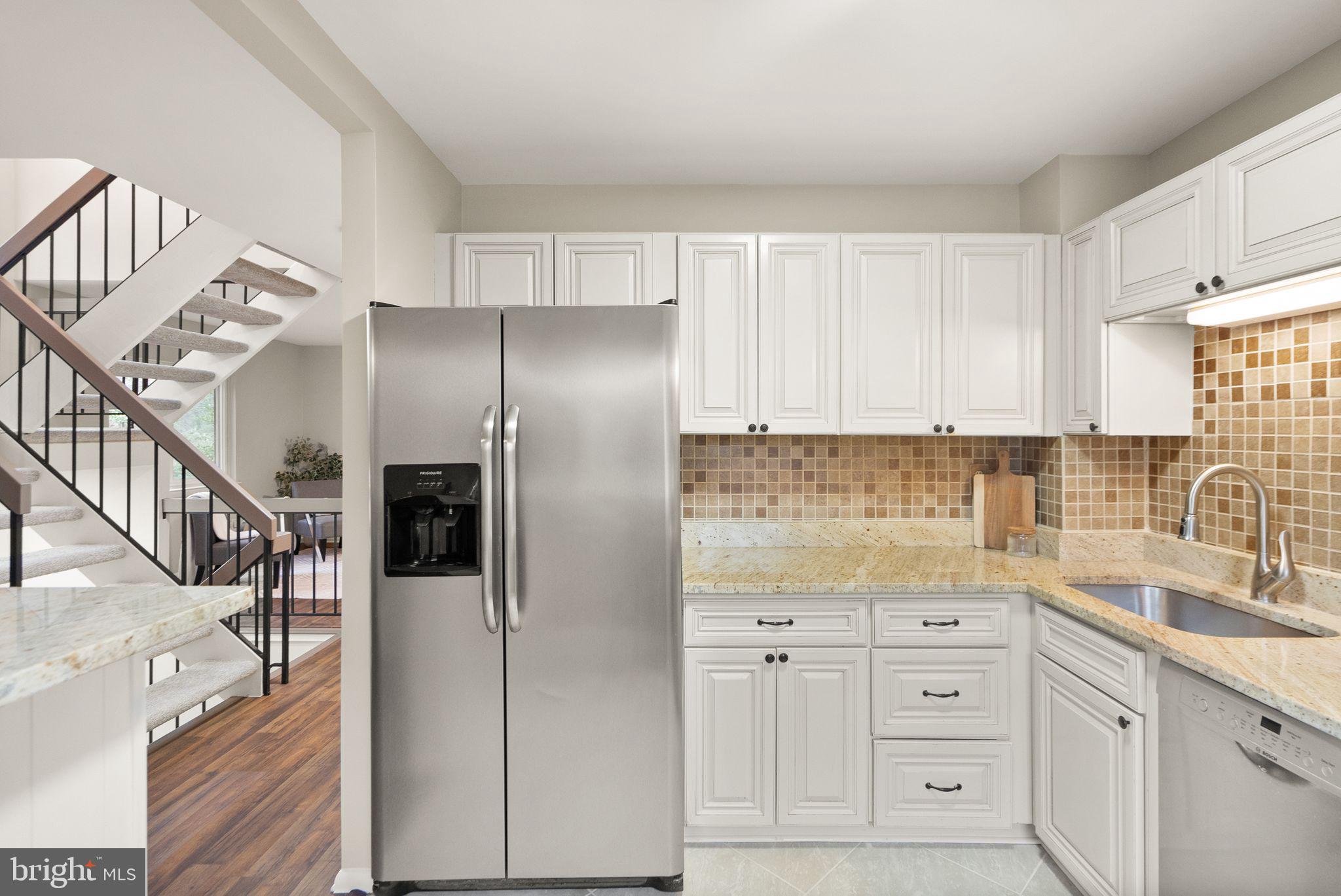 11801 Coopers Court Reston, VA 20191 - Photo 21 of 66 a kitchen with granite countertop a refrigerator a sink and white cabinets