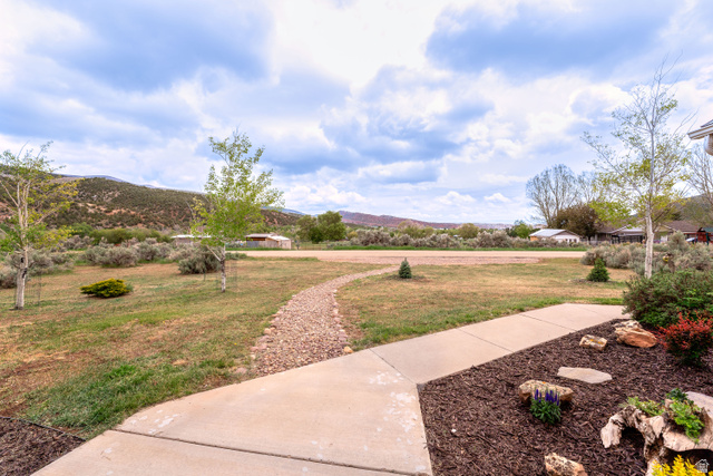 7343 North Sawtooth Cv Road Vernal, UT 84078 - Photo 54 of 64 Manicured front yard with mature trees, a concrete pathway, and a decorative rock path
