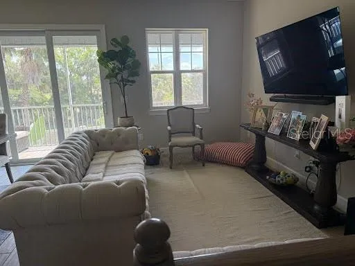 a living room with furniture a flat screen tv and a floor to ceiling window