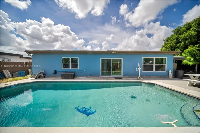 a backyard of a house with table and chairs plants and large tree