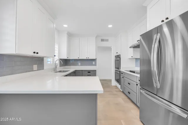 a kitchen with stainless steel appliances a refrigerator sink and white cabinets