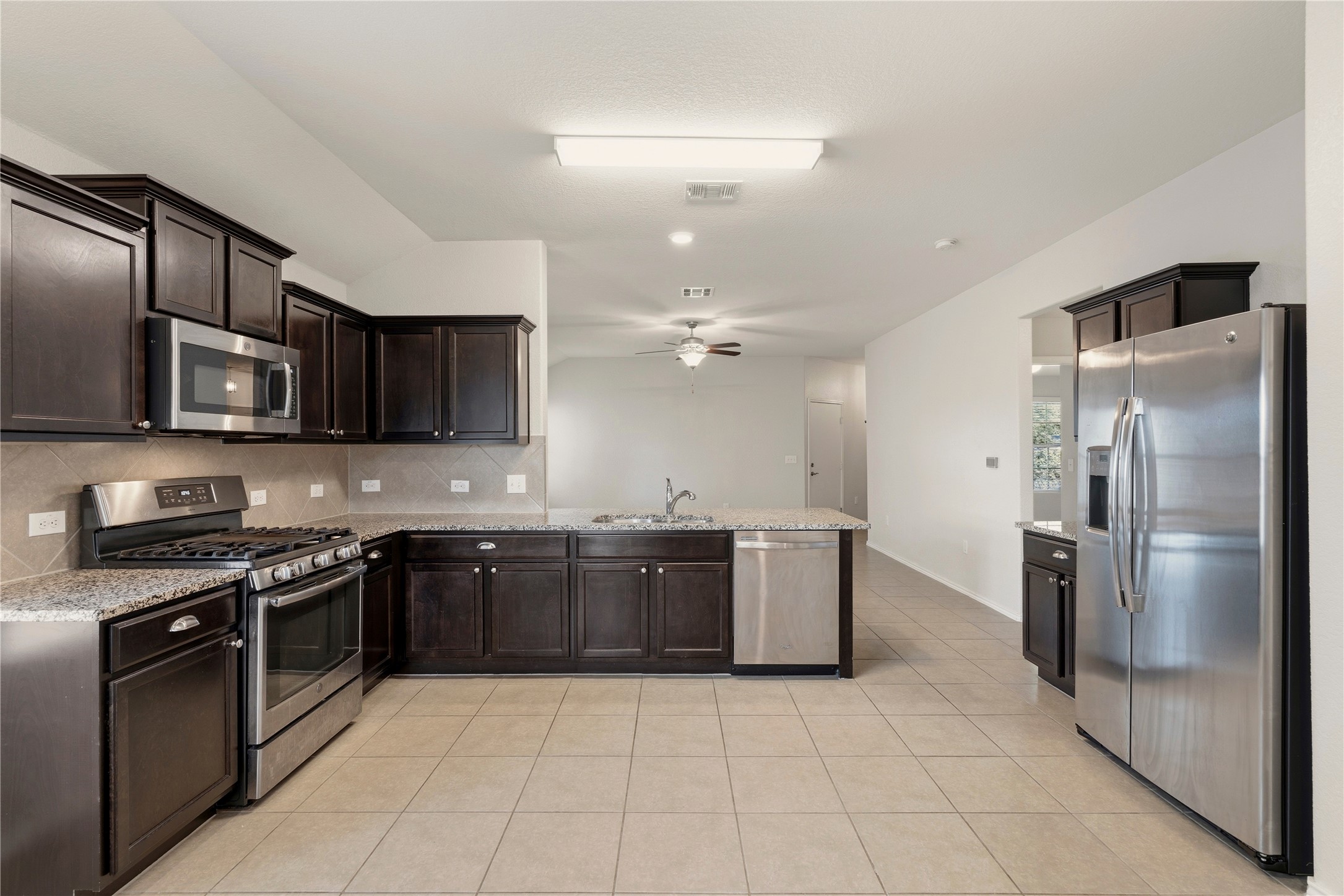 3721 Alpine Autumn Drive Austin, TX 78744 - Photo 11 of 29 a large kitchen with stainless steel appliances granite countertop a stove a refrigerator and a microwave