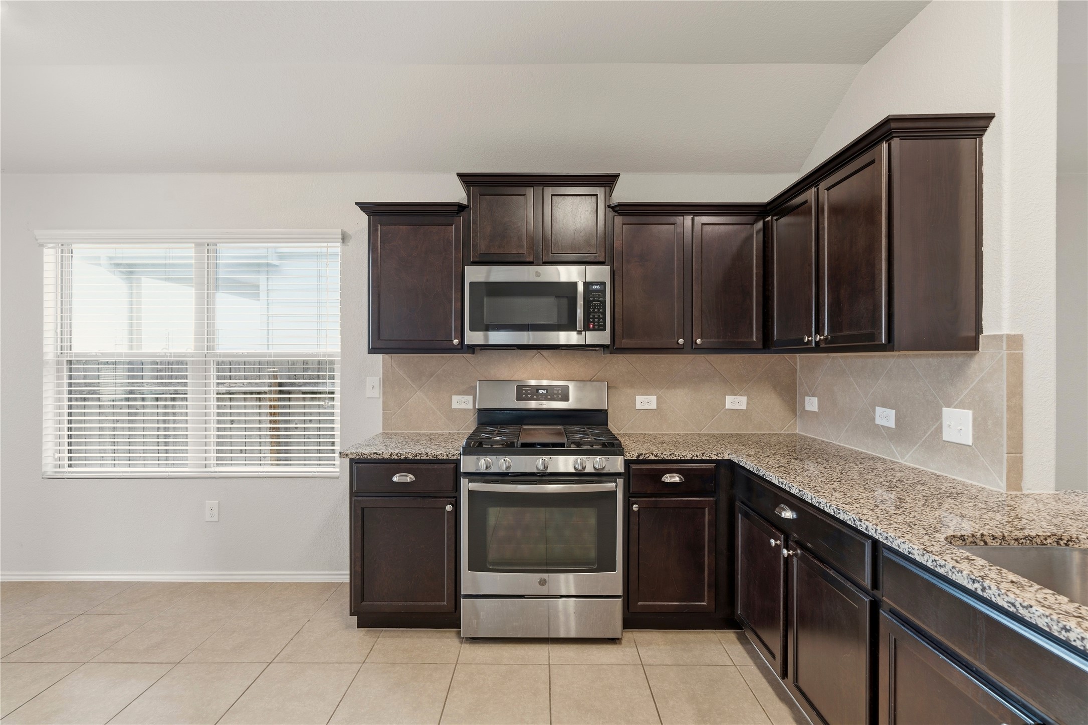 3721 Alpine Autumn Drive Austin, TX 78744 - Photo 12 of 29 a kitchen with granite countertop wooden cabinets and a stove top oven