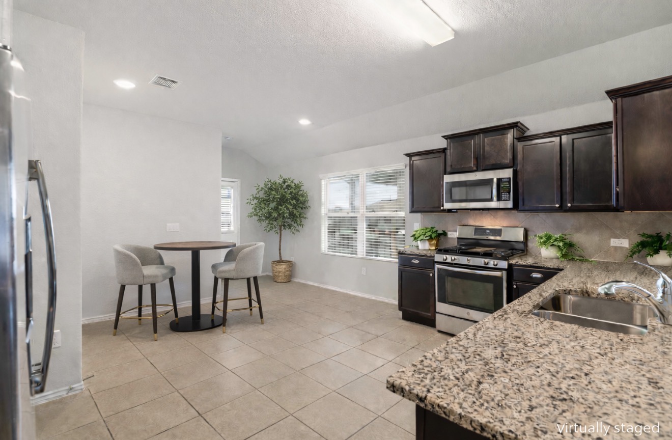 3721 Alpine Autumn Drive Austin, TX 78744 - Photo 9 of 29 a kitchen with stainless steel appliances granite countertop a stove top oven a sink a dining table and chairs