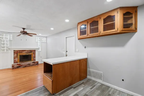 a living room with stainless steel appliances kitchen island a stove wooden floor and a fireplace