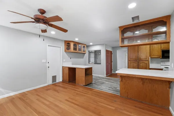 a view of empty room with wooden floor and fan